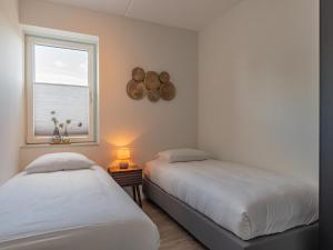 two beds in a room with a window at Het Havenverblijf in Kamperland