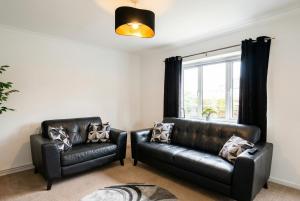 a living room with two leather chairs and a window at Contemporary Private Home Near Nottingham with Free Parking and Garden in Sandiacre