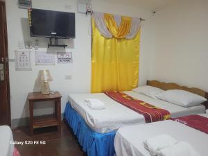 two beds in a room with a tv on the wall at Knights-Apple Inn in Mambajao
