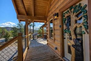 a front porch of a cabin with a tree mural on the door at Makin' Memories cabin in Sevierville +27 photos