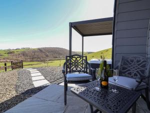 a patio with two chairs and a table with wine glasses at Cennin Pedr in Ruthin