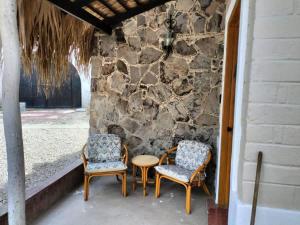 a group of chairs and a table and a stone wall at Sandy Shores Cabaña 4 in La Paz