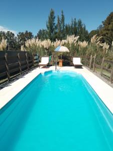 a swimming pool with two chairs and an umbrella at Cabañas Campos del Parana in San Pedro