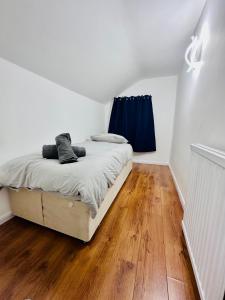 a white bedroom with a bed with blue curtains at Reading Central Haven in Reading