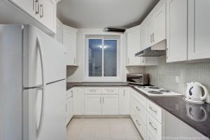 a white kitchen with white cabinets and a white refrigerator at Quiet Suites Up to 8 Guests Near DTVan Monthly Option in West Vancouver