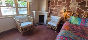 a room with a bed and two chairs and a fireplace at Sandy Shores Cabaña 10 in La Paz