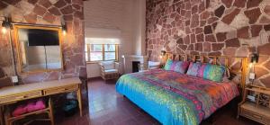a bedroom with a bed and a stone wall at Sandy Shores Cabaña 10 in La Paz