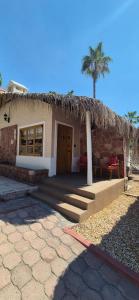 a building with a straw hut with a palm tree at Sandy Shores Cabaña 10 in La Paz