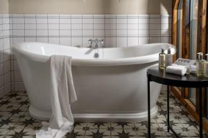 a white bath tub in a bathroom with a table at The Fleece at Cirencester in Cirencester +47 photos