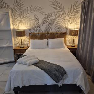 a bedroom with a bed with white sheets and plants on the wall at 05 on Mc Donald in Kirkwood