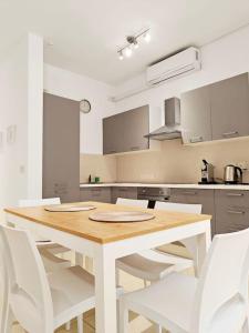 a kitchen with a wooden table and white chairs at Hilltop Retreat in Kalkara
