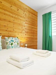 a bedroom with a white bed with a wooden wall at Hilltop Retreat in Kalkara