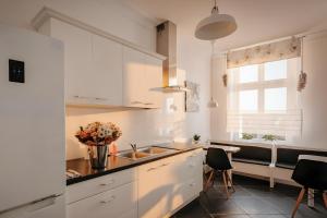 a kitchen with white cabinets and a sink and chairs at Dwie Wieże in Międzyzdroje