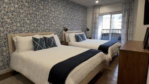 two beds in a room with floral wallpaper at Spacious 1 Bed with Mountain Views only steps from Downtown in Canmore