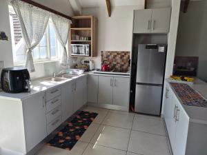 a kitchen with white cabinets and a refrigerator at Cape Dutch Flair in Durbanville