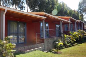 une maison rouge avec une terrasse couverte et une cour dans l'établissement Le Chat'o Park Hotel Ivato Airport NAVETTE GRATUITE H24, à Antananarivo