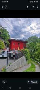 a picture of a red house with a boat in front of it at Villa Amaranta Room and Breakfast in Edolo