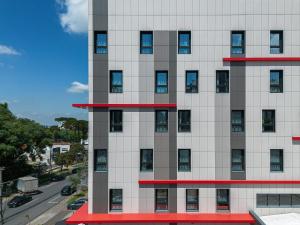 a tall white building with red trim at Hotel Moov Curitiba in Curitiba