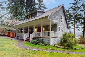 a large white house with a porch on a lawn at Shore Thing Retreat in Eastsound
