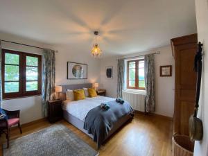 a bedroom with a bed and two windows and a chandelier at Soulages in Najac +39 photos
