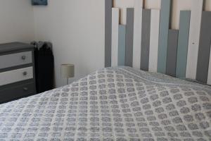 a bed with a gray and white comforter on it at Maison de Gilydie in Chabris