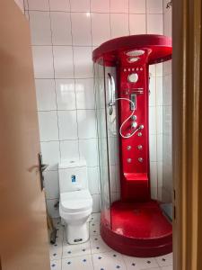 a red machine in a bathroom with a toilet at Centenary Gardens BnB in Kigali