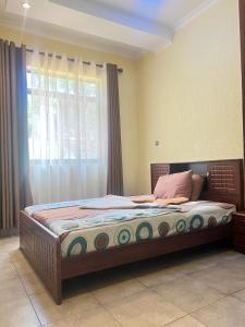 a large bed in a room with a window at Centenary Gardens BnB in Kigali
