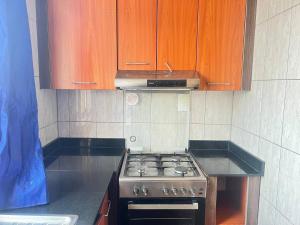 a kitchen with a stove and wooden cabinets at Centenary Gardens BnB in Kigali +2 photos