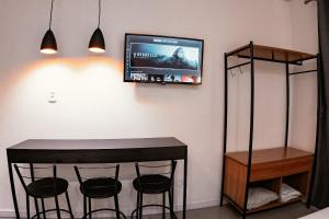 a room with a bar with stools and a tv on the wall at Urban Studio in Blumenau