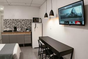 a kitchen with a refrigerator and a television on a wall at Urban Studio in Blumenau