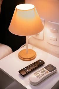 a lamp and a remote control sitting on a table at Urban Studio in Blumenau