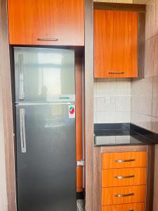 a kitchen with a refrigerator and wooden cabinets at Centenary Gardens BnB in Kigali