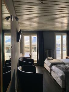 a bedroom with two beds and chairs and windows at Hotel Le Terminus in Mons