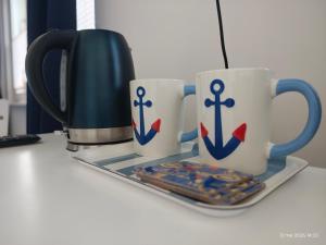 two coffee mugs with crosses on them on a counter at Gryfhaus - Pokój Bosmański, kameralny, 22 m2, parking, Wi-Fi, blisko morza, wysoka ocena 9,9 in Międzyzdroje