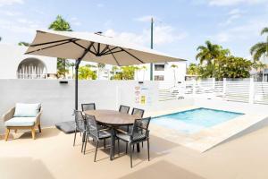 a table and chairs with an umbrella next to a swimming pool at AQUA Casa A-8 - Vibrant & FUN 3 BR House with Pool in Dorado