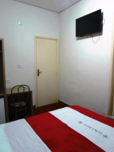 a bedroom with a red and white bed and a flat screen tv at Hotel Minho SP - Melhor Opção do Centro - Café da Manhã Incluso - Perto do Metrô, 25 de Março e Brás - 10 Min do Allianz Parque, 11 Min do Expo Center Norte e 9 Min do Distrito Anhembi in São Paulo