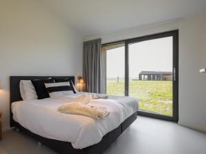 a bedroom with a large bed with a large window at Natuurhuis Houtkant in Wissenkerke