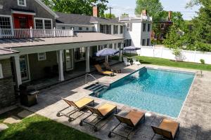 ein Swimmingpool mit Liegestühlen und Sonnenschirmen neben einem Haus in der Unterkunft Dock Square House in Kennebunkport