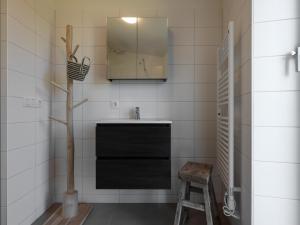 a bathroom with a sink and a mirror and a stool at Natuurhuis Houtkant in Wissenkerke +27 photos
