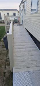 a wooden walkway next to a house with a bench at 128 Lido Beach in Prestatyn