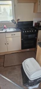a kitchen with a black stove and a white toilet at 128 Lido Beach in Prestatyn