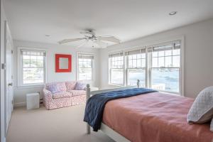 a bedroom with a bed and a chair and windows at Mother`s Beach House in Kennebunk