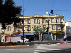 a yellow building with a white car parked in front of it at Hotel Minho SP - Melhor Opção do Centro - Café da Manhã Incluso - Perto do Metrô, 25 de Março e Brás - 10 Min do Allianz Parque, 11 Min do Expo Center Norte e 9 Min do Distrito Anhembi in São Paulo