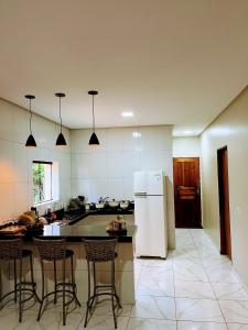 a kitchen with a refrigerator and some chairs in it at aconchego da serra in Coronel José Diaz