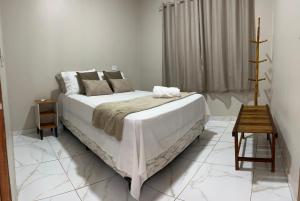 a white bedroom with a large bed and a table at aconchego da serra in Coronel José Diaz