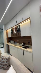 a kitchen with white cabinets and a couch at top one in Taif