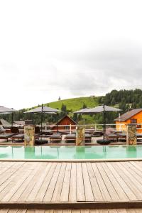 a swimming pool with tables and umbrellas on a wooden deck at Гук готельно-ресторанний комплекс in Bukovel