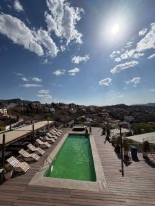 a swimming pool on a deck with chairs and the sun at Hotel 1988 Guanajuato in Guanajuato