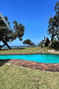 a swimming pool in the grass next to a house at Berna Coastal Retreat in Port Shepstone