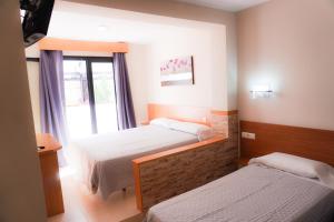 a hotel room with two beds and a window at Hostal Costabella in Fuengirola